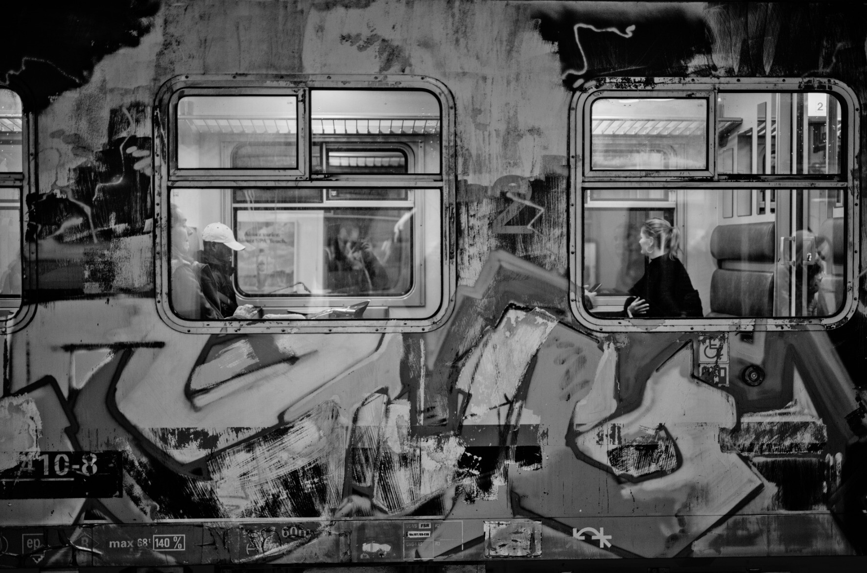 Photo in Namur train station, too many layers, 2022Trains with multiple layers of graffiti partially removed and multiple layers of people view in the train.